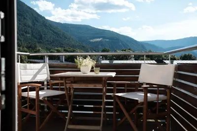 a table and chairs on a balcony with mountains at Residence Panorama in Brunico
