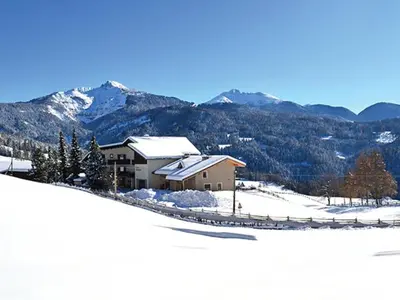 a house on a snowy hill with mountains in the background at Residence Scheidnerhof in Aldino