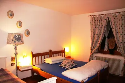 a bedroom with a bed with blue sheets and a lamp at Garni Biancaneve Ruffrè-Mendola in Mendola