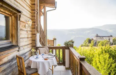 a table on the balcony of a house at Apartments Schlossblick Naturholz in Vols am Schlern