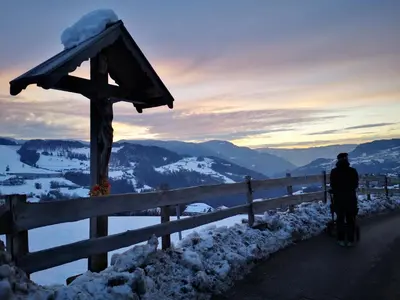 a man standing next to a fence in the snow at Apartments Schlossblick Naturholz in Vols am Schlern