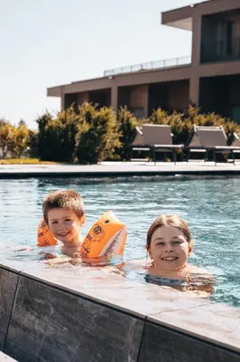 two children in a swimming pool wearing life jackets at Das Mühlwald - Quality Time Family Resort in Naz-Sciaves