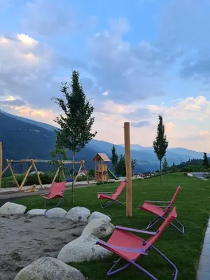a group of pink chairs sitting on the grass at Das Mühlwald - Quality Time Family Resort in Naz-Sciaves
