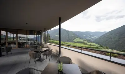 a restaurant with tables and chairs and a view of mountains at Das Mühlwald - Quality Time Family Resort in Naz-Sciaves