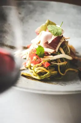 a plate of food with pasta and vegetables on it at Wiesenhof Gardenresort in San Leonardo in Passiria