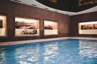 a large swimming pool in a room with paintings at Wiesenhof Gardenresort in San Leonardo in Passiria