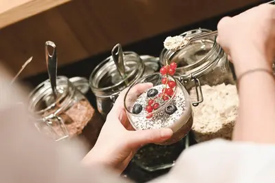 a person holding up a dessert in a glass jar at Wiesenhof Gardenresort in San Leonardo in Passiria