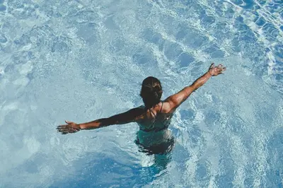 a woman in a pool of water with her arms out at Wiesenhof Gardenresort in San Leonardo in Passiria
