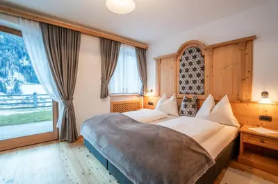 a bedroom with a large bed and a large window at Residence Cesa Ladina in Ortisei