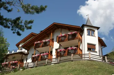a house with flowers on balconies on a hill at Residence Cesa Ladina in Ortisei