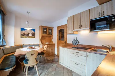 a kitchen with wooden cabinets and a table and a sink at Residence Cesa Ladina in Ortisei