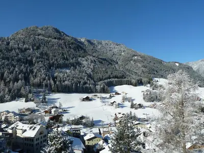a village covered in snow with a mountain in the background at Residence Cesa Ladina in Ortisei