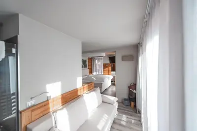 a living room with white furniture and a large window at Chalet Vites Mountain Hotel in Canazei