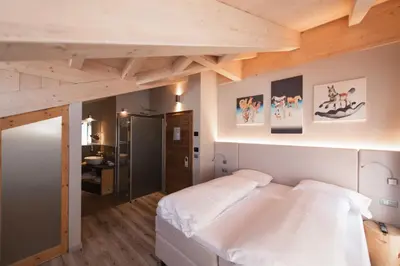a bedroom with a white bed and wooden ceilings at Chalet Vites Mountain Hotel in Canazei