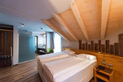 a bedroom with a large bed with wooden ceilings at Chalet Vites Mountain Hotel in Canazei