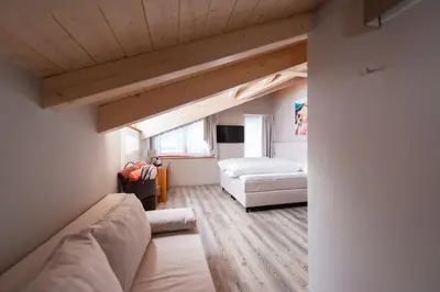 a living room with a couch and a bed at Chalet Vites Mountain Hotel in Canazei