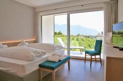 a bedroom with a bed and a desk and a large window at Hotel Flora in Lagundo