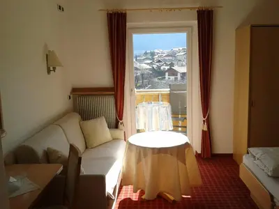 a living room with a couch and a table and a window at Hotel Flora in Lagundo