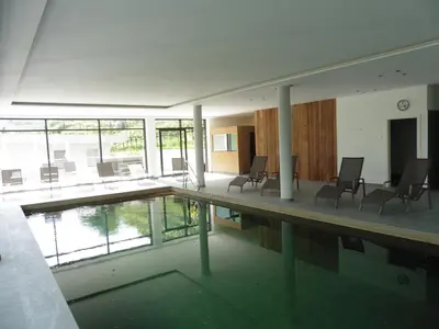 a swimming pool in a building with chairs at Hotel Flora in Lagundo