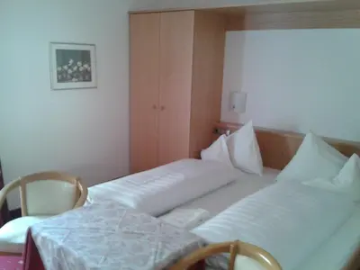 a hotel room with two beds and a table at Hotel Flora in Lagundo