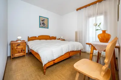 a bedroom with a bed and a table with a vase on it at Residence Weiss in Vigo di Fassa