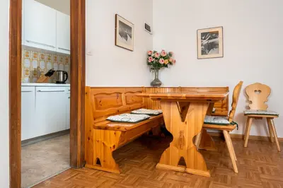 a kitchen with a wooden table and a table and chairs at Residence Weiss in Vigo di Fassa