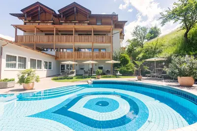 a house with a swimming pool in front of a building at Wanderhotel Teiserhof in Funes