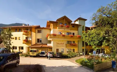 a large building with cars parked in a parking lot at Wanderhotel Teiserhof in Funes
