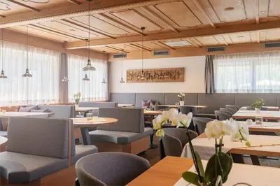 a restaurant with tables and chairs and windows at Wanderhotel Teiserhof in Funes