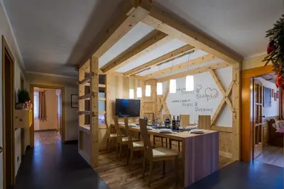 a room with a long table with chairs and a tv at Alpin Apartments Colfosco in Colfosco