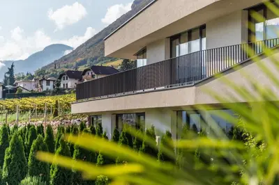 a building with a balcony next to a vineyard at Hof im Kalch Tramin in Termeno