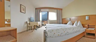 a hotel room with a bed and a desk at Garni Pöhl in Tirolo
