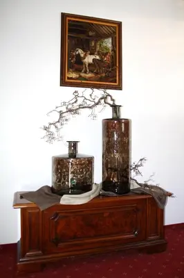 a table with two vases and a painting on the wall at Garni Pöhl in Tirolo