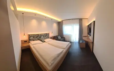 a bedroom with a large bed and a television at Garni Pöhl in Tirolo