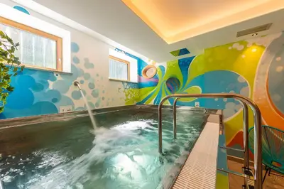 a bathroom with a swimming pool with a mural at Hotel Al Lago in Soraga
