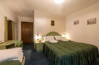 a hotel room with two beds and a desk at Hotel Al Lago in Soraga