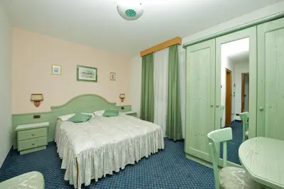 a bedroom with a bed and a dresser and a bed sidx sidx sidx sidx at Hotel Al Lago in Soraga