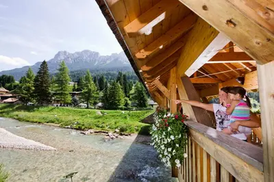 two girls are looking out of a wooden building at Hotel Al Lago in Soraga