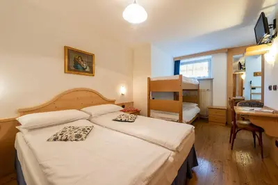 a hotel room with a bed and a desk and a desk at Hotel Al Lago in Soraga