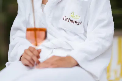 a person in a white shirt with a glass of liquid at Hotel Eichenhof in Tirolo