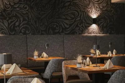 a restaurant with wooden tables and chairs and a wall at Hotel Eichenhof in Tirolo