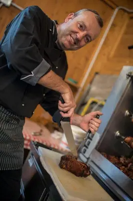 a man cutting a piece of meat with a knife at Hotel Eichenhof in Tirolo