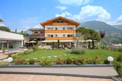 a building with a garden with flowers in front of it at Hotel Eichenhof in Tirolo