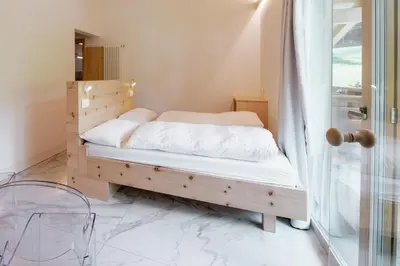 a bedroom with a wooden bed with white sheets at Garnì Aurora Bed and Breakfast in Soraga