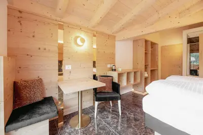 a bedroom with a bed and a desk and chairs at Garnì Aurora Bed and Breakfast in Soraga