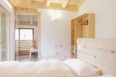 a bedroom with a white bed and wooden walls at Garnì Aurora Bed and Breakfast in Soraga