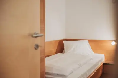 a bed with white sheets in a room at Weihergut in Cermes
