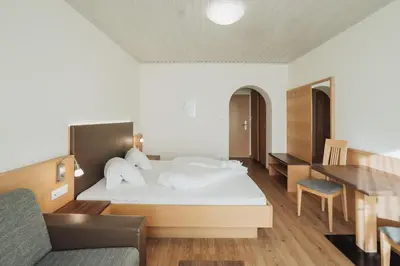 a bedroom with a bed with white sheets and a desk at Weihergut in Cermes