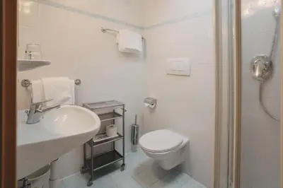 a white bathroom with a toilet and a sink at Weihergut in Cermes