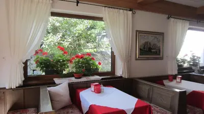 a room with two tables and a window with flowers at B&B Bucaneve in Vigo di Fassa
